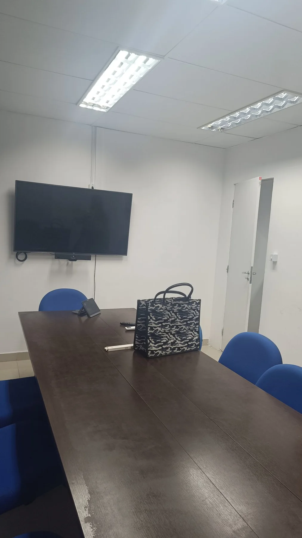 Antes: sala de reunião com paredes brancas, mesa escura e cadeiras azuis comuns