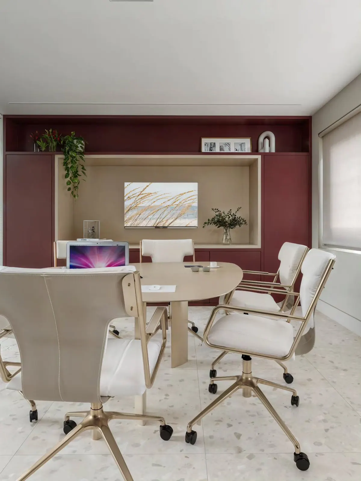 Render de sala de reunião vibrante com marcenaria em tom vinho e mesa redonda clara